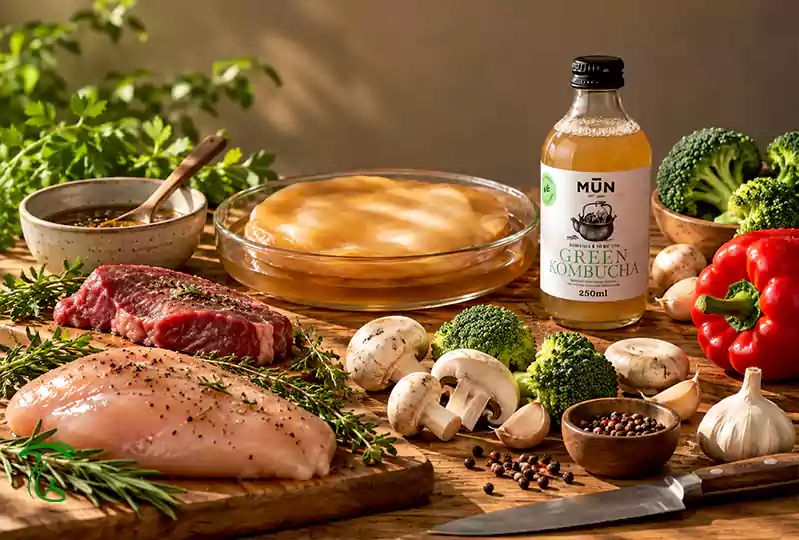 شیشه کامبوچا کنار مرغ، گوشت، قارچ و سبزیجات برای ماریناد